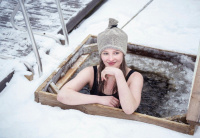 En tjej har mössan på sig när hon badar i en isvak 